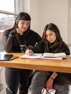Non binary artist and non-binary student drawing indoors