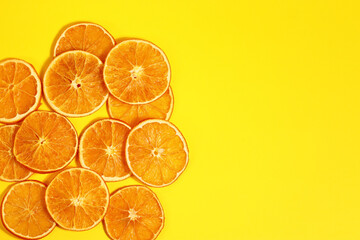 Dried slices of orange fruit on yellow paper background.