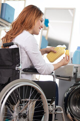 woman in wheelchair by washing machine pouring fabric conditioner