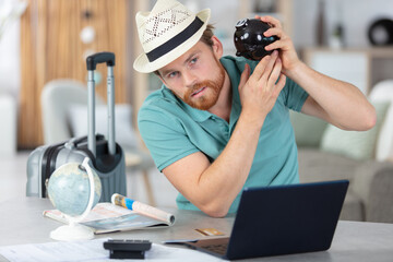 man shaking piggy-bank needing funds for travelling