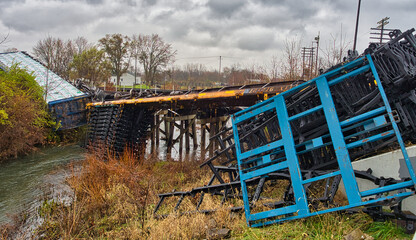 Train derailment over a small bridge on a rainy day.