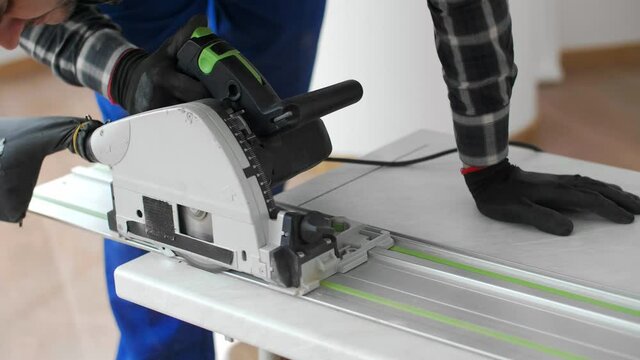 A carpenter cutting a wooden board on the floor of the room