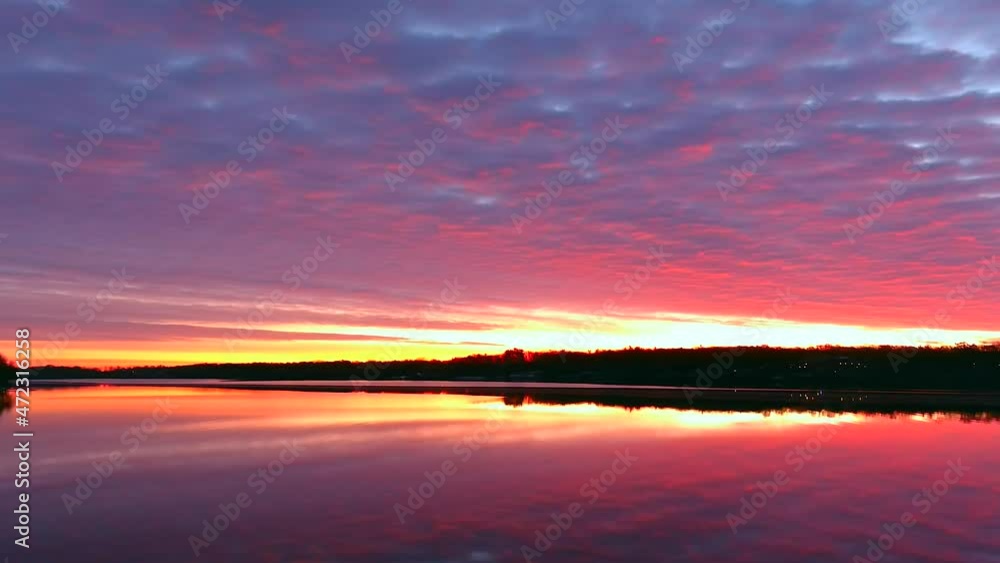Wall mural perfect slow panning view of tranquil water reflecting sunrise with red clouds and colorful sky. thi