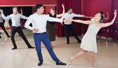 Happy cheerful pleasant people learning to dance waltz in dancing class