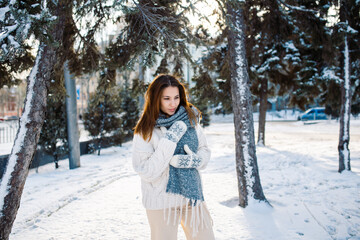 A beautiful woman walks in a winter park against the backdrop of snow-covered trees. Blur nature background.