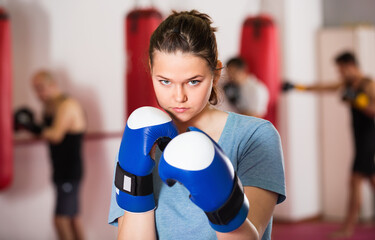Portrait of cheerful positive female sportswear training in colored boxing gloves