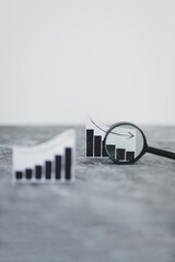 financial markets or money and investments, charts showing upward and downward trends next to each other with magnifying glass analysing one of them