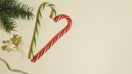 Christmas banner with lollipops and Christmas tree twigs on beige background. Copy space.