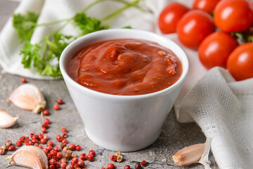 Bowl with organic tomato sauce on grunge background