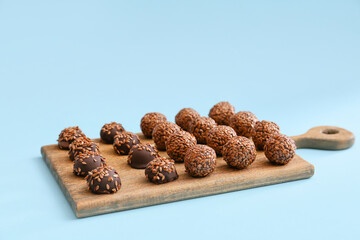 Board with tasty flax seed candies on color background