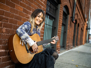 Young female Indigenous artist playing guitar outdoors