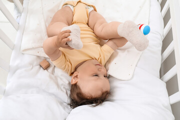 Obraz na płótnie Canvas Cute little baby with toy lying in comfy crib