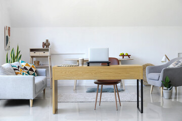 Wooden table with laptop and cup of coffee in interior of modern room