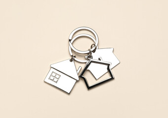 Silver house shaped keychains with keyrings on beige background