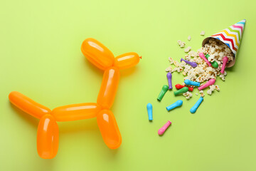 Dog made of balloon, popcorn and party hat on color background
