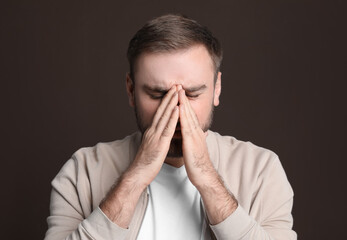 Young man suffering from headache on dark background