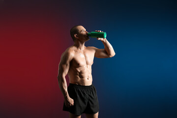 Male bodybuilder drinking protein shake on dark background