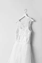 Hanger with beautiful wedding dress on light background, closeup