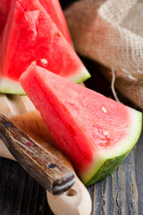a piece of fresh watermelon with a knife on a rustic background