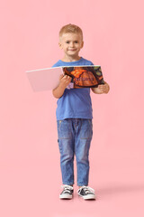 Adorable little boy with book on pink background