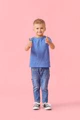 Adorable little boy in blue t-shirt showing thumbs-up on pink background