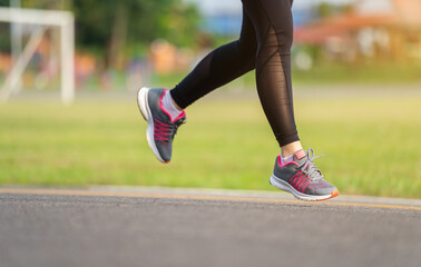 closeup woman feet running on road in park