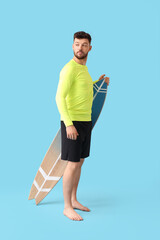 Handsome bearded man with surfboard on blue background