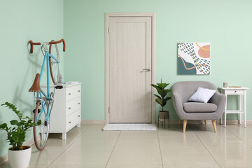 Interior of stylish living room with bicycle, chest of drawers and armchair