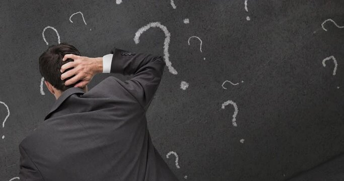 Rear view of confused caucasian businessman scratching head, with question marks on chalkboard - Powered by Adobe