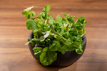 Green watercress in bowl on the table.