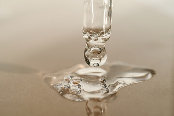 The texture of serum or oil with a pipette on a beige background.