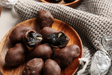 Delicious chocolate candies with prunes in plate on table, closeup