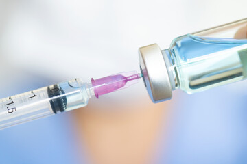 doctor's hand holds a syringe and a blue vaccine bottle at the hospital. Health and medical concepts.