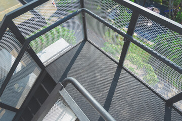 Top view of black metal steps with safety balustrade of fire escape outside of high building