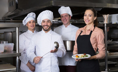 Team of restaurant staff posing together in modern professional kitchen