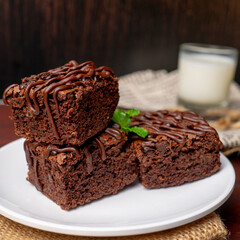 Chocolate Brownies with a glass of milk on white plate and wooden table