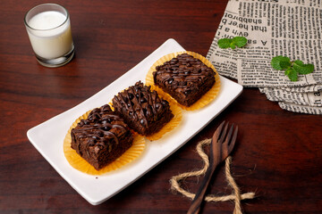 Chocolate Brownies with a glass of milk on white plate and wooden table