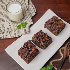Chocolate Brownies with a glass of milk on white plate and wooden table