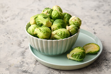Bowl with ripe raw Brussels cabbage on color background
