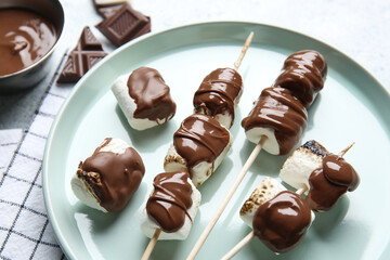 Plate of tasty grilled marshmallows with chocolate on light background