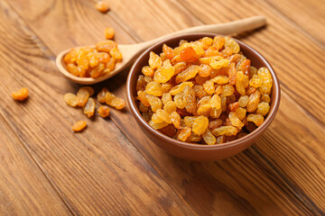Bowl with sweet raisins on wooden background, closeup