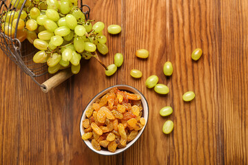 Bowl with tasty raisins and ripe grapes in basket on wooden background