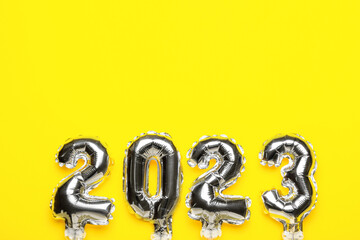 Figure 2023 made of silver balloons on yellow background