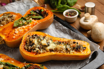 Baking dish with tasty stuffed pumpkins on wooden background