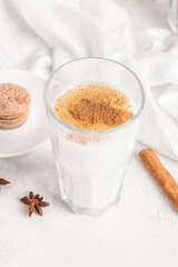 Glass of tasty coffee with cinnamon on white background
