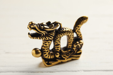 Figurine of Chinese dragon on white wooden background