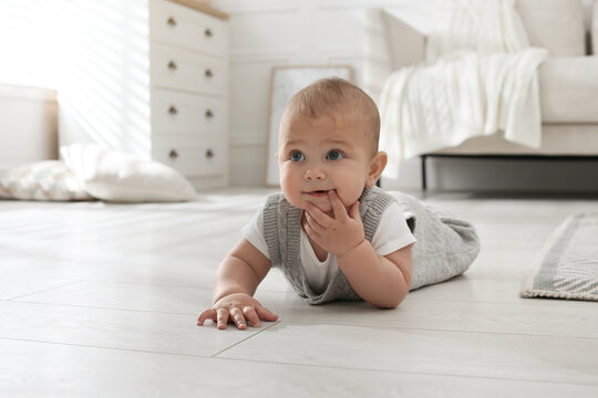 Cute baby crawling on floor at home