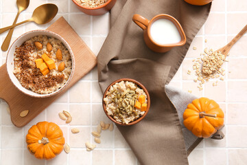 Bowls of tasty oatmeal with pumpkin on tile background