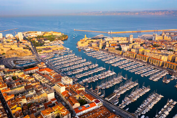 Fototapeta na wymiar Picturesque drone view of modern Marseille cityscape on Mediterranean coast overlooking large Old Port with moored pleasure yachts on sunny day, France