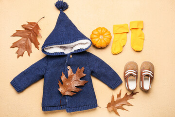 Stylish baby clothes, shoes, pumpkin and autumn leaves on color background